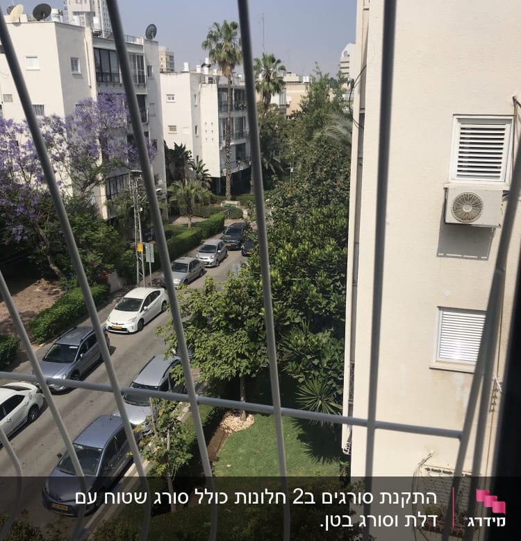 סורגים לבנים על חלון עם נוף עירוני